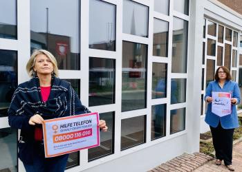 Gleichstellungsbeauftragte Regina Lenneps und Bürgermeisterin Ulrike Westkamp halten Plakate zum Orange Day gegen häusliche Gewalt 